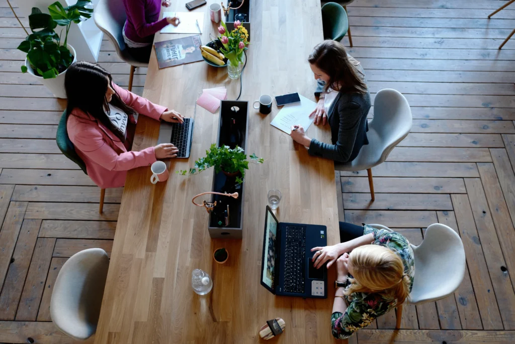 L'équipe de ContentSEO travaillant ensemble autour d'une grande table en bois, utilisant des ordinateurs portables et des notes manuscrites, illustrant la collaboration et l'engagement dans un environnement de travail moderne et dynamique.